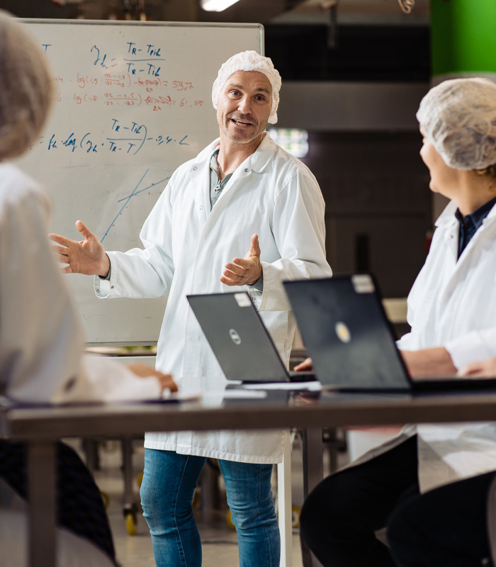 Begeleider en cursisten les in het lab - Leergang Quality and Business Improvement in Food