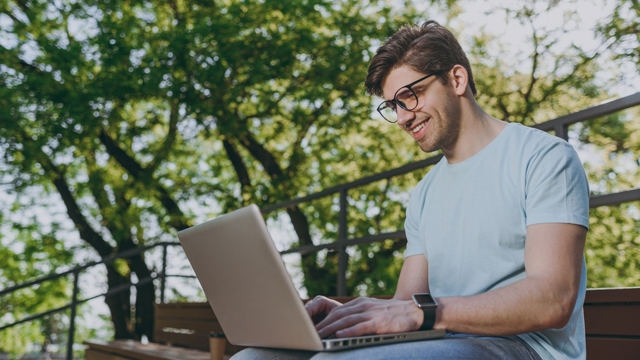 young man with laptop working in park