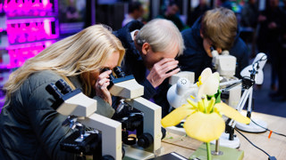 Bezoekers kijken door microscoop op de open dag in Den Bosch