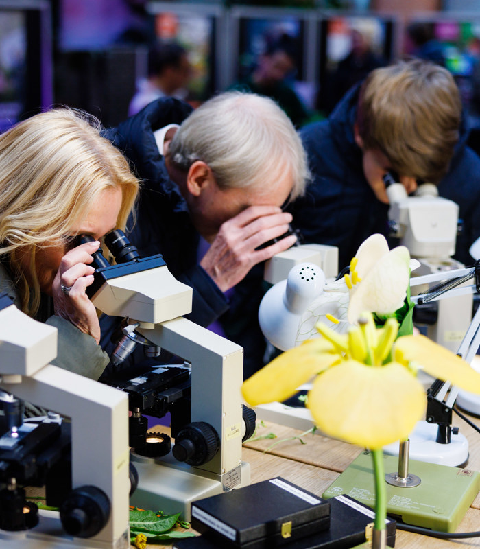 Bezoekers kijken door microscoop op de open dag in Den Bosch