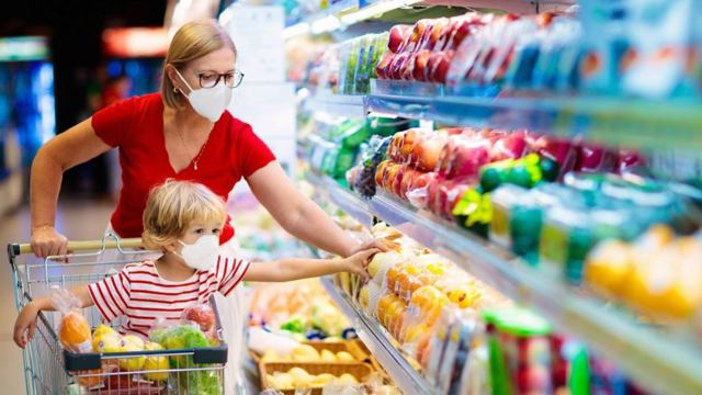 Moeder en zoon met mondkapje in supermarkt