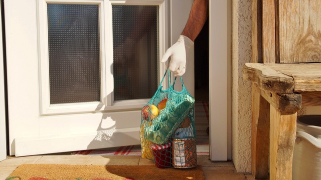 hand met handschoen pakt boodschappentas