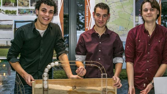 Studenten staan bij model en posters van Breuken Beleven